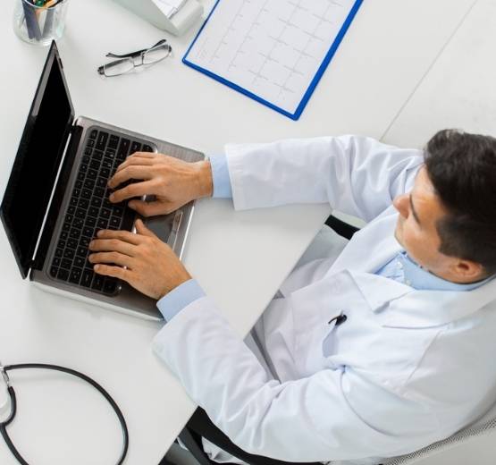Doctor in white coat working at a laptop