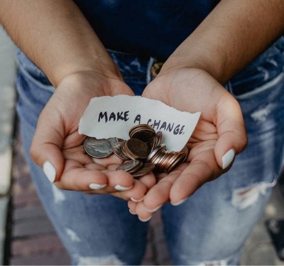 Lady holding handful of coins with sign that reads 'make a change'