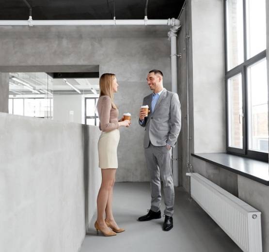 Man and woman stood in an office corridor talking
