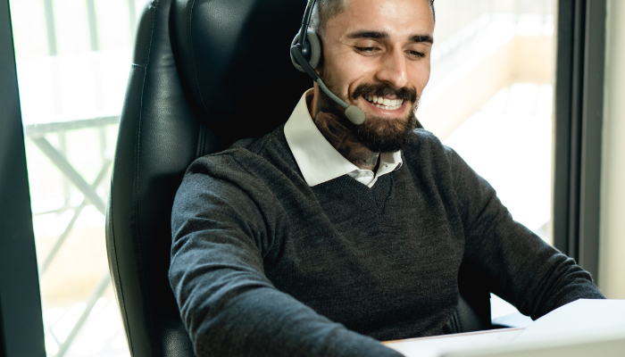 Male customer service operative wearing a headset and using Microsoft Dynamics 365 Copilot to assist in resolving issues with a customer swiftly with AI-based suggestions.