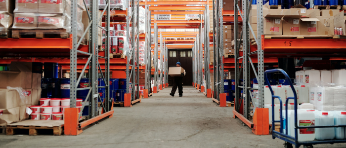 Man carrying a box, blurred in the distance inside a warehouse owned by a business that tracks KPIs for growth.
