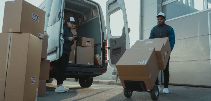 Two people unloading packages that have been returned by customers, which will be processed through NetSuite following the company's reverse logistics strategy.