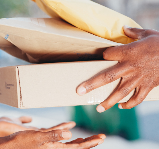 Close up image of a person handing over packages and parcels to another to denote the retail challenge of deliveries from online purchases.