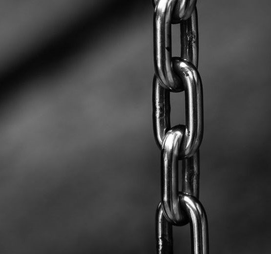 Greyscale image of a metal chain hanging vertically which denotes a strong business supply chain in retail and wholesale distribution.